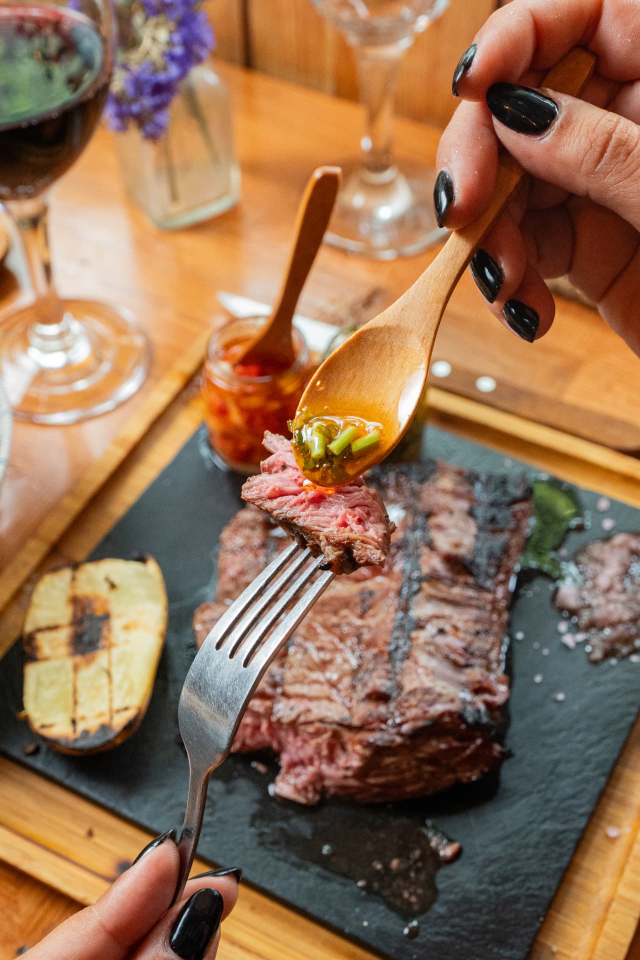A slice of grilled steak topped with chimichurri on a fork
