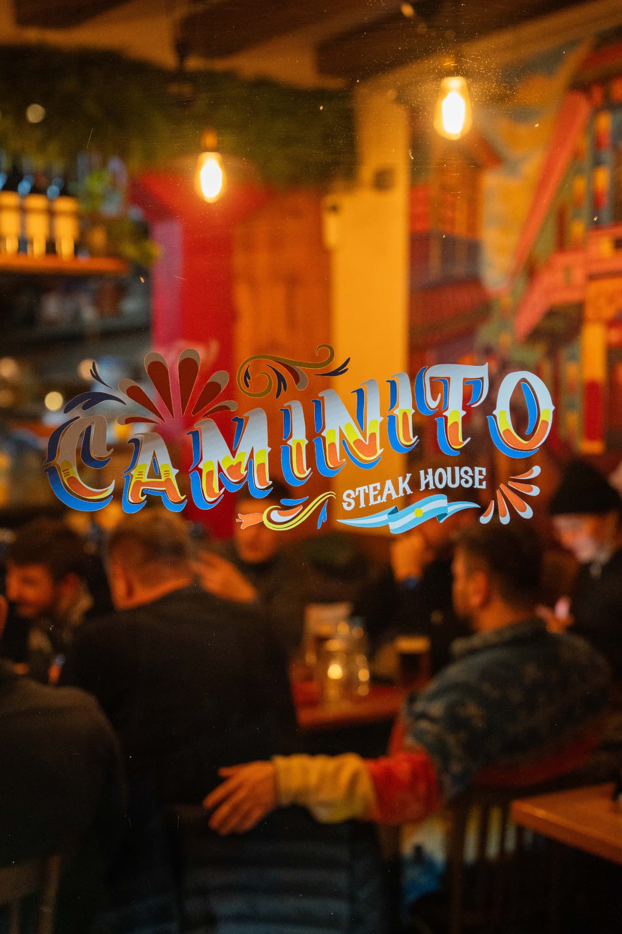 Caminito Grill Steakhouse logo glowing on the window at night