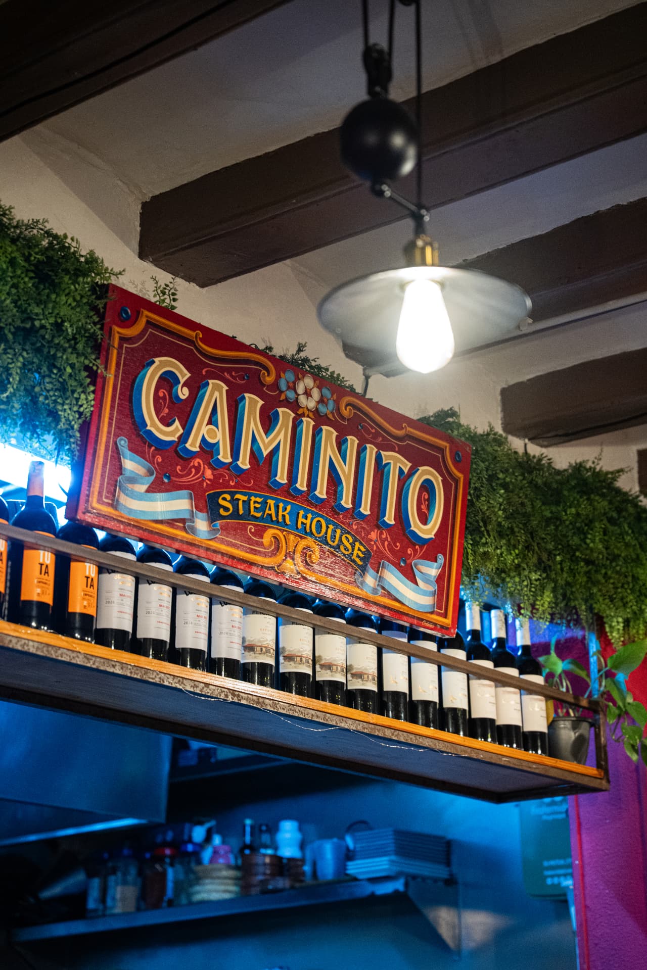 Hand-painted Caminito Steak House sign above the wine shelf